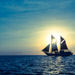 Sailing ship Ombak Putih silhouetted against the sun while cruising indonesia.