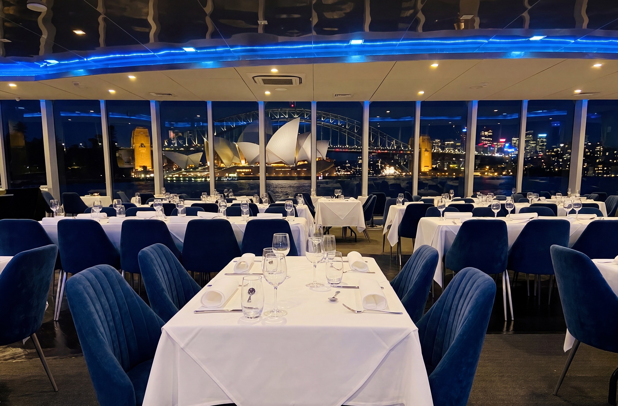 Vibrant view of the illuminated Opera House and Harbour Bridge from inside the Clearview Vivid Sydney Cruise